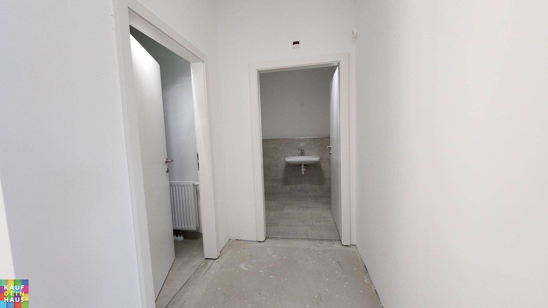 Flur mit Zugang zu zwei separaten Toilettenräumen, einer davon mit Waschbecken.