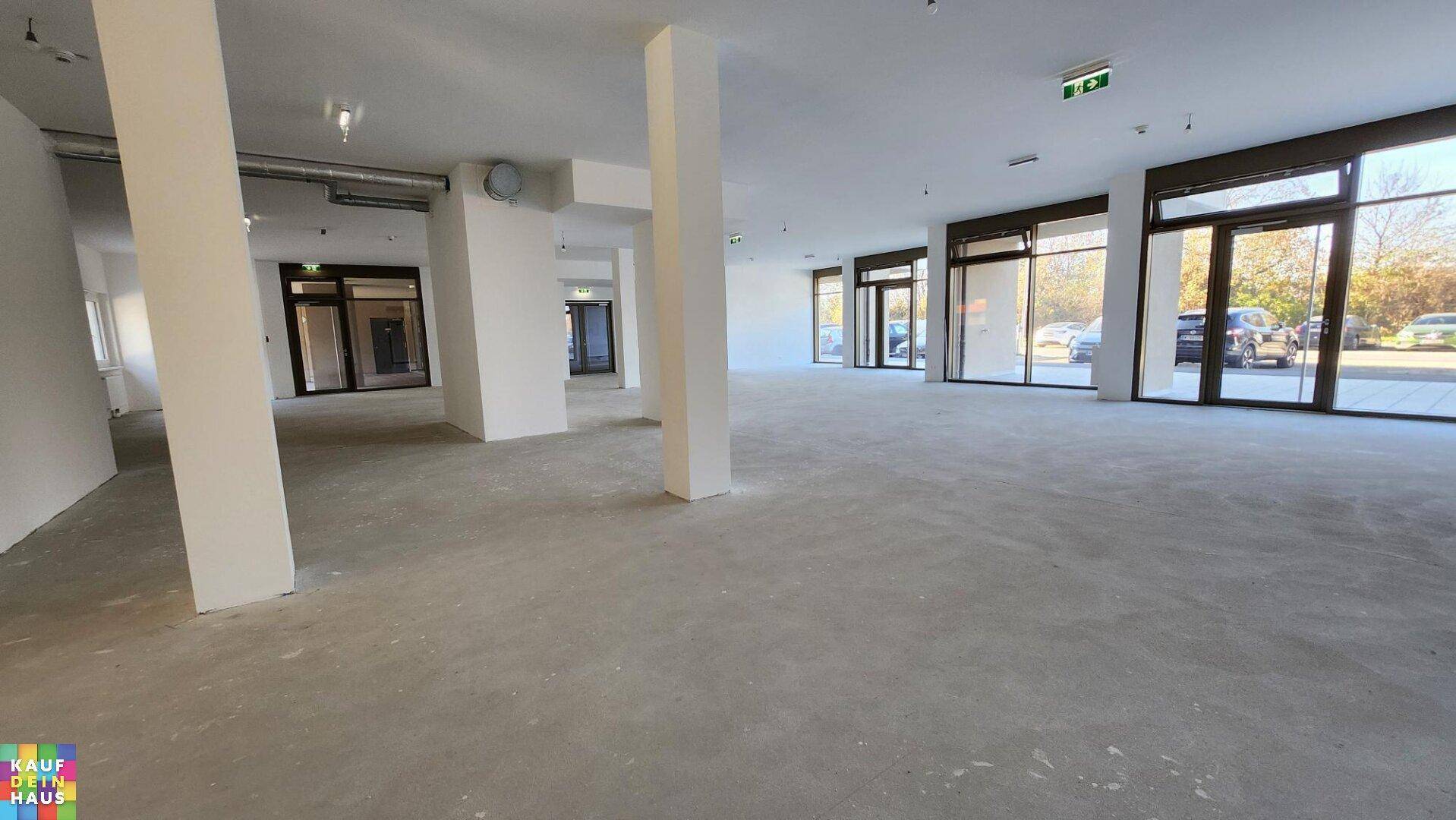 Weitläufiger Gewerberaum mit vielen großen Fensterfronten, die viel Tageslicht hereinlassen.