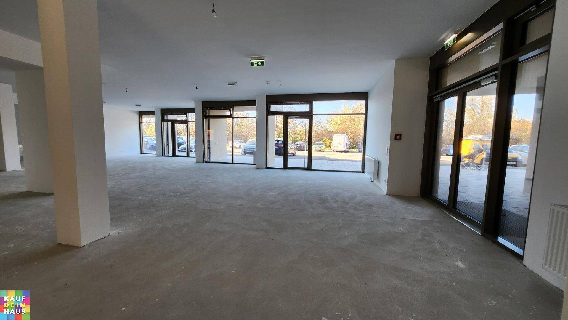 Heller und offener Gewerberaum mit Betonboden und einer Reihe von großen Fenster- und Türfronten.