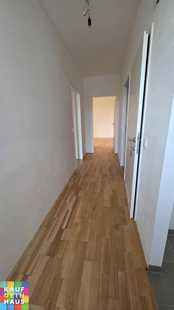 Heller Flur mit Holzparkettboden, der zu verschiedenen Zimmern der Wohnung führt.