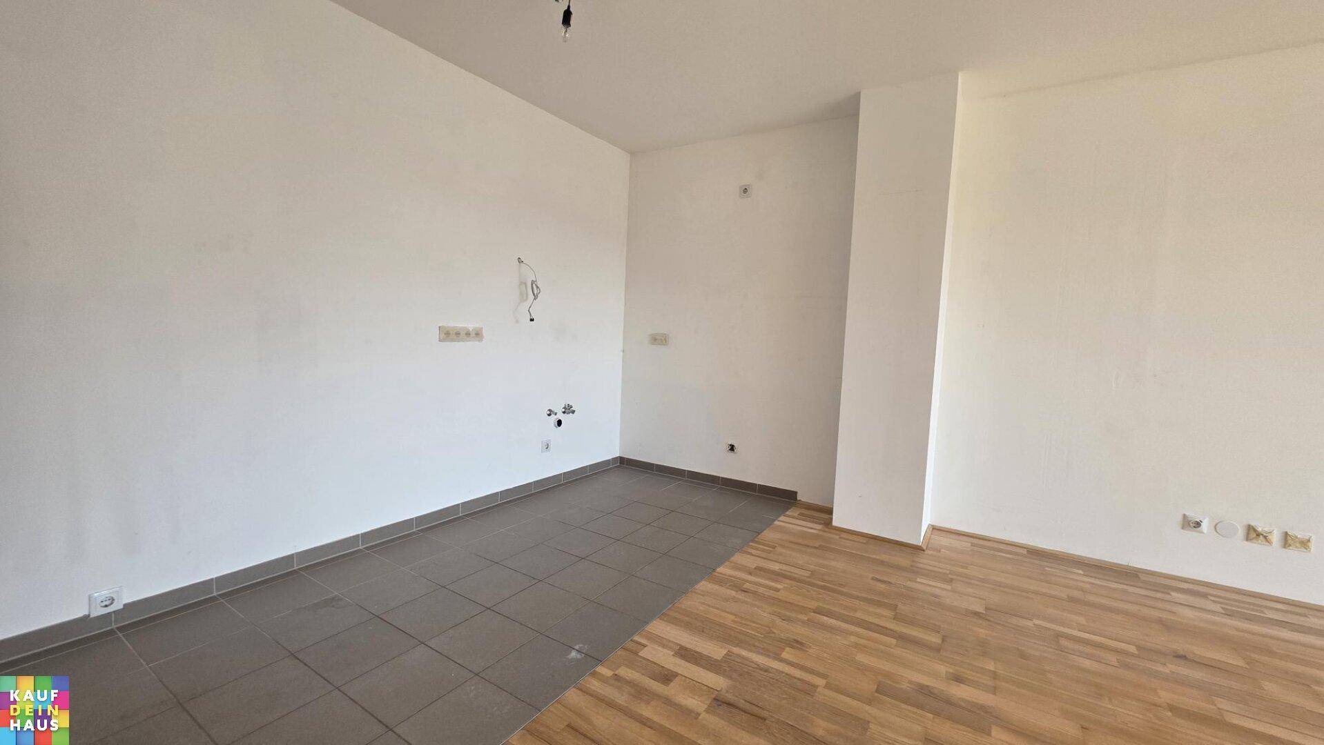 Bereich mit Fliesenboden und Anschlüssen, möglicherweise für eine zukünftige Küche vorgesehen.