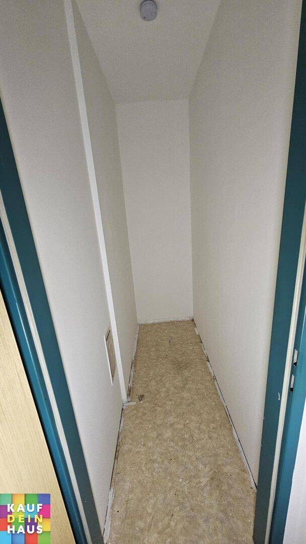Schmaler, leerer Abstellraum mit unfertigem Boden, ideal für zusätzlichen Stauraum.