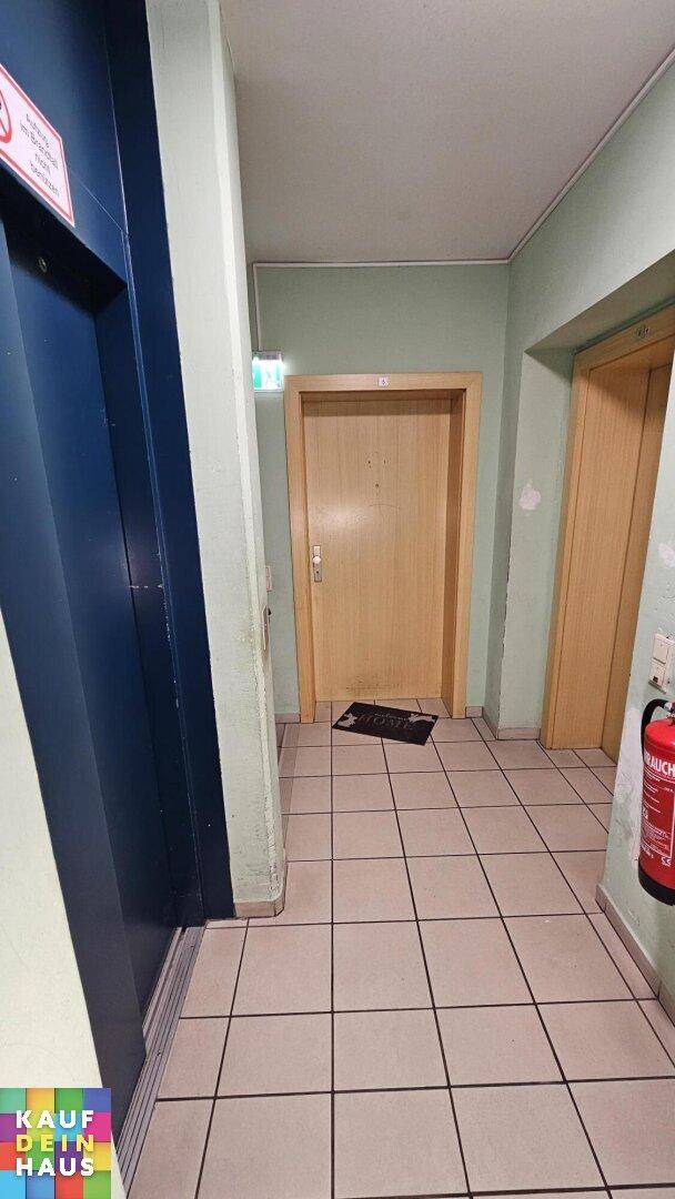 Gemeinschaftsflur mit Aufzug, gefliestem Boden und Brandschutzvorrichtung, im Eingangsbereich gelegen.