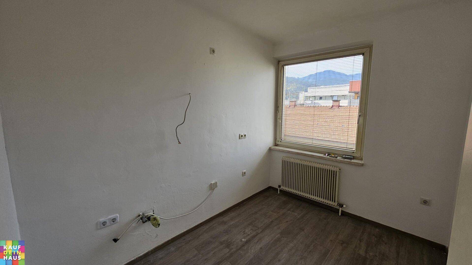 Zimmer mit modernem Laminatboden, Fenster und vorbereiteten Anschlüssen für Elektronik.