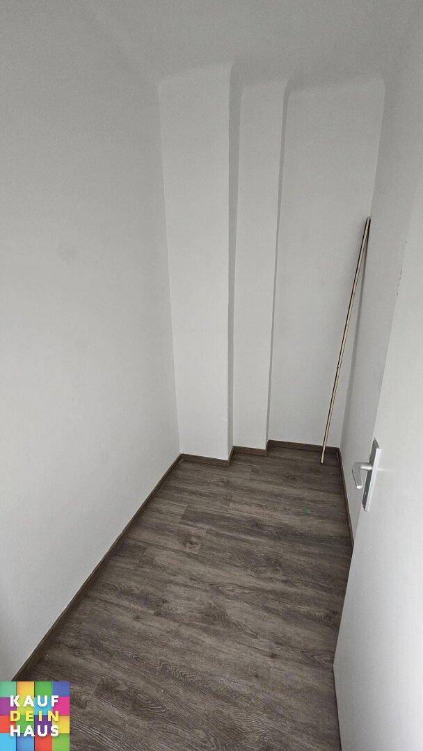 Praktischer Abstellraum mit Laminatboden und weißen Wänden für zusätzlichen Stauraum.