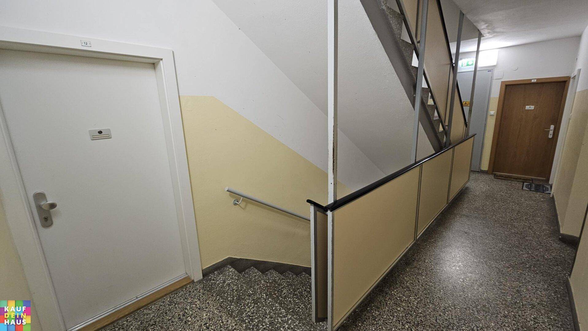 Treppenhaus und gemeinschaftlicher Flurbereich mit Terrazzoboden und Handlauf.