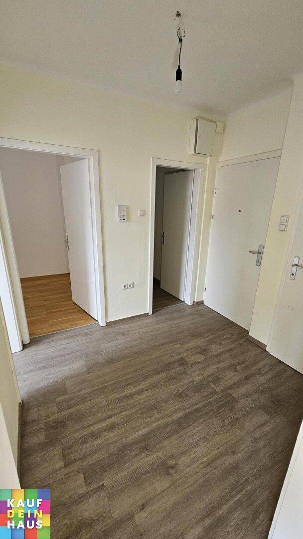 Heller Flur mit Laminatboden und Zugang zu mehreren Zimmern der Wohnung.
