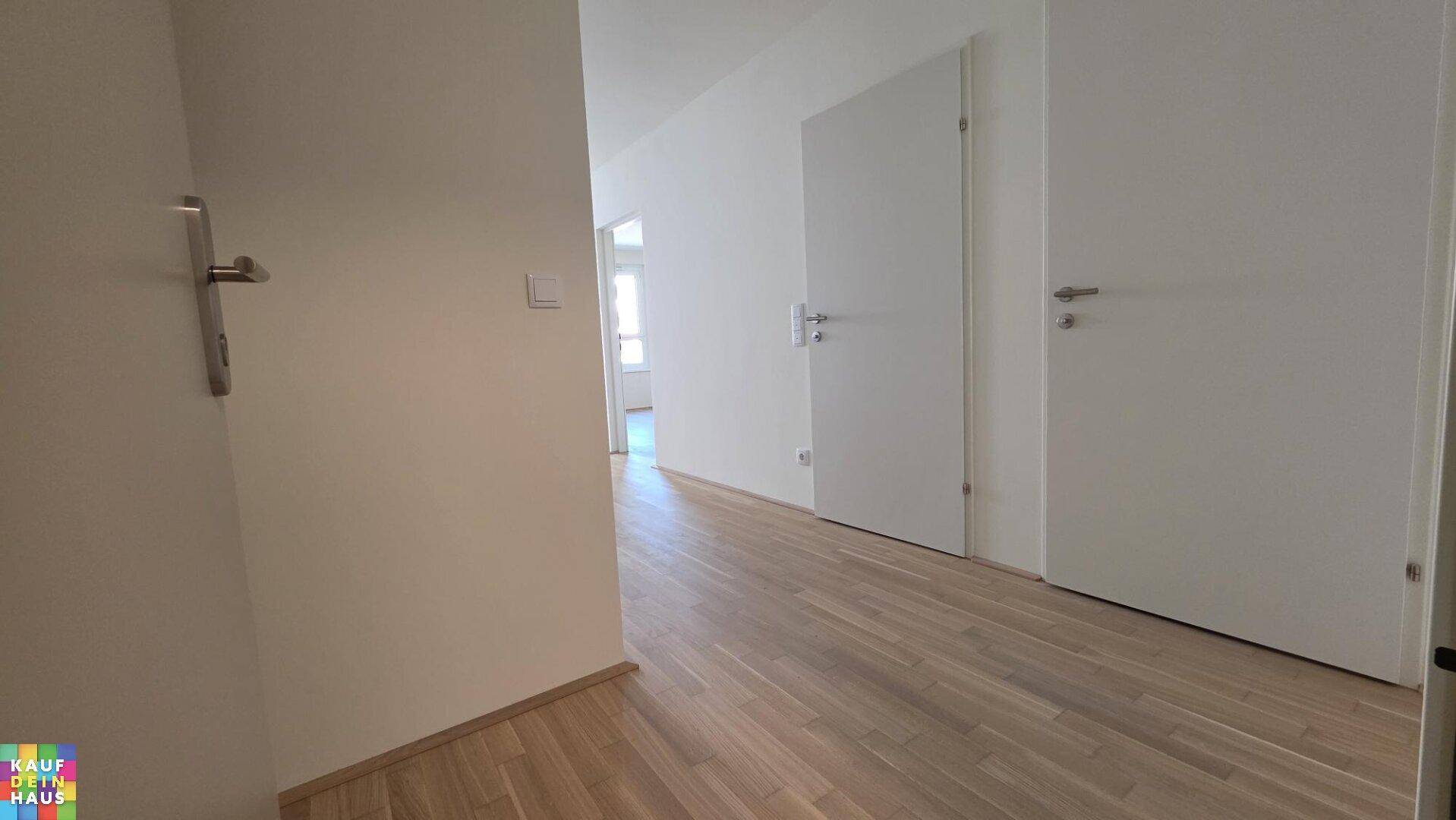Heller Flur mit modernem Laminatboden und weißen Türen, der zu weiteren Räumen führt.