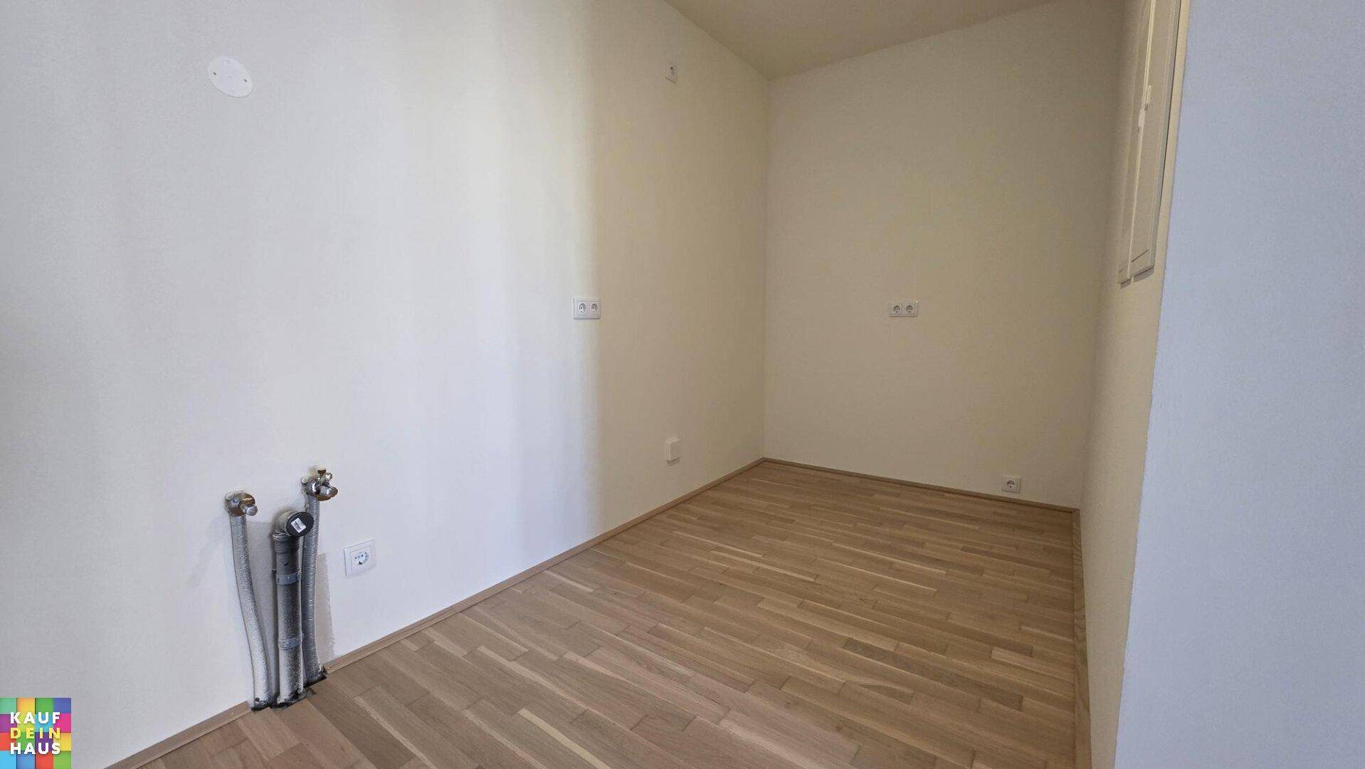 Heller Raum mit Laminatboden und sichtbaren Anschlüssen, ideal als Hauswirtschaftsraum oder kleine Küche.