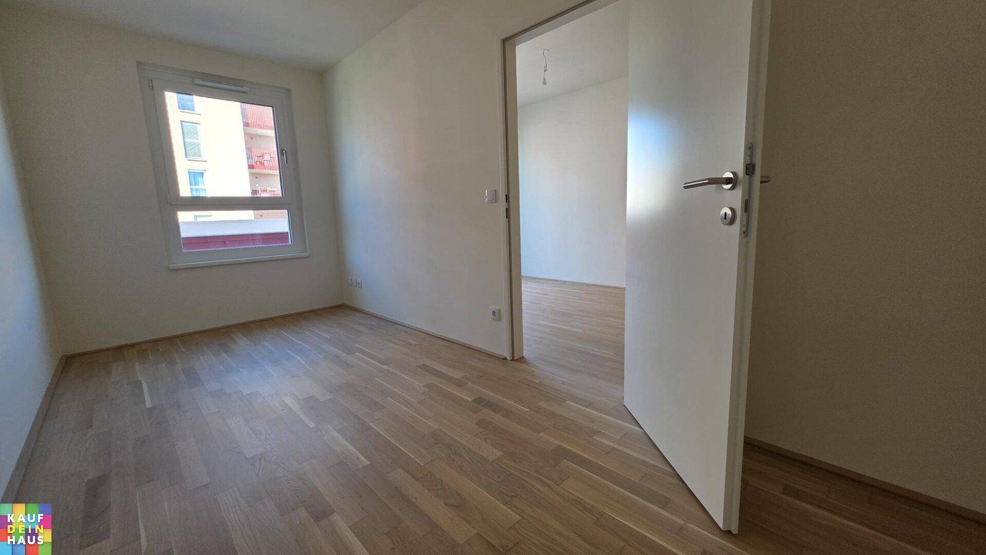 Helles Schlafzimmer mit Laminatboden, weißen Wänden und einem Fenster für natürliches Licht.