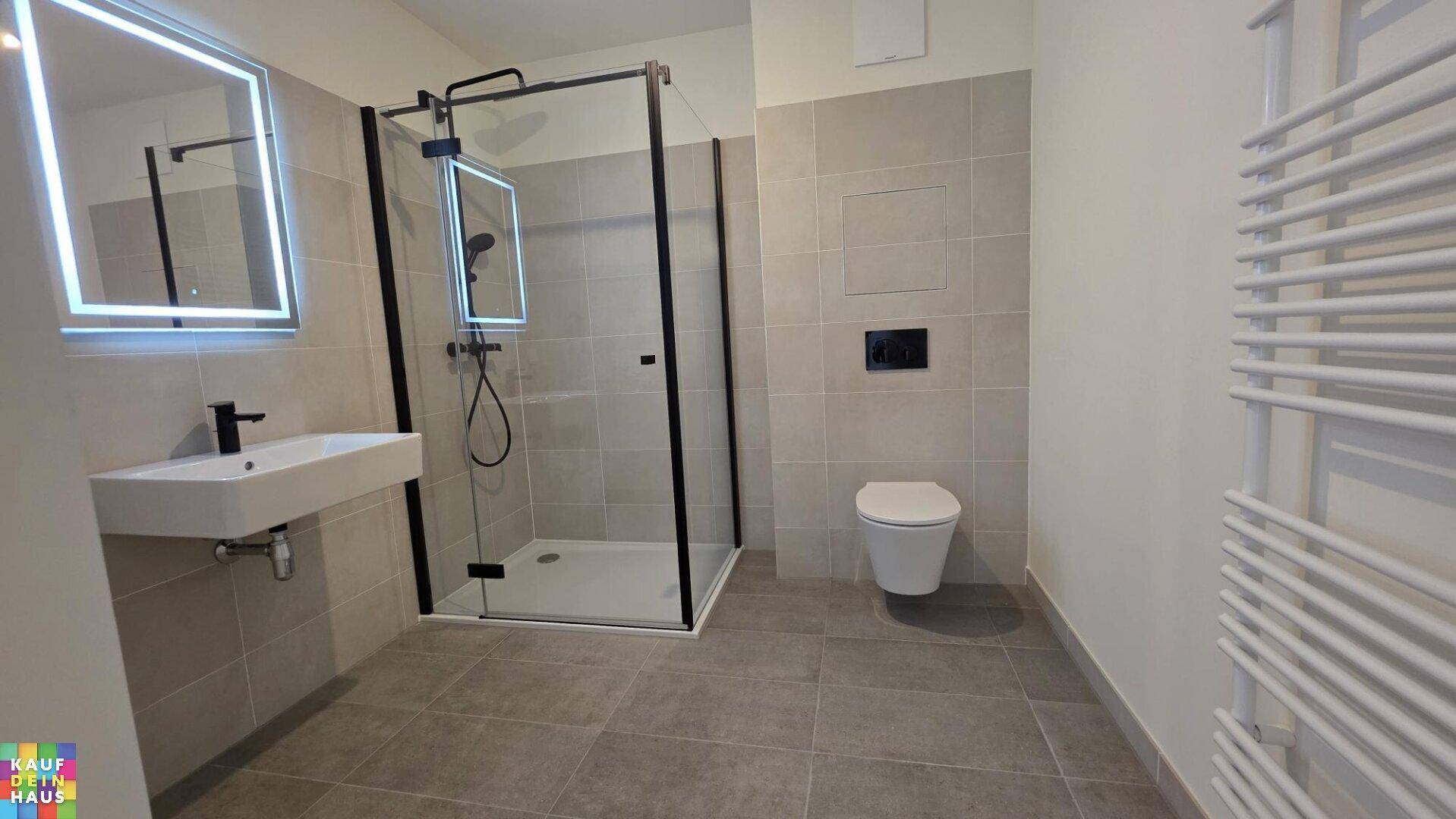 Modernes Badezimmer mit ebenerdiger Dusche, WC und beheiztem Handtuchhalter.