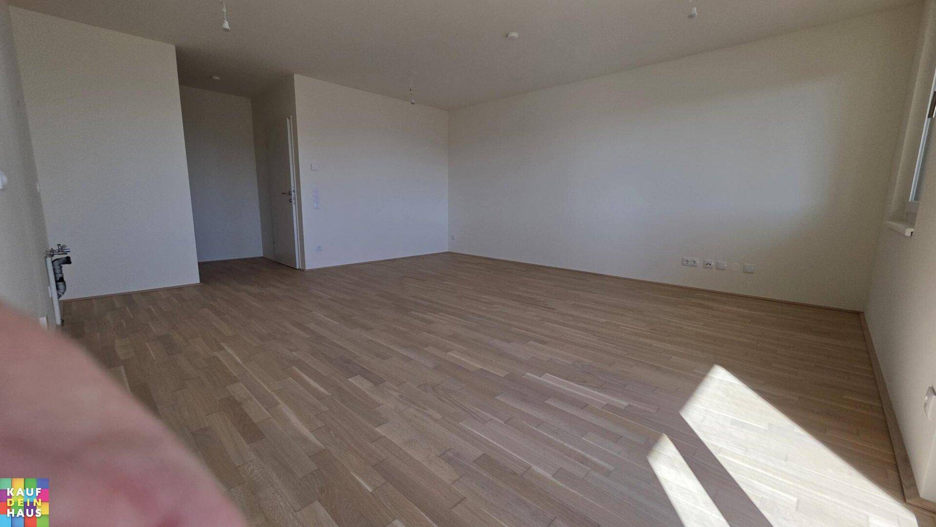 Geräumiger Wohnbereich mit Parkettboden und viel Tageslicht.