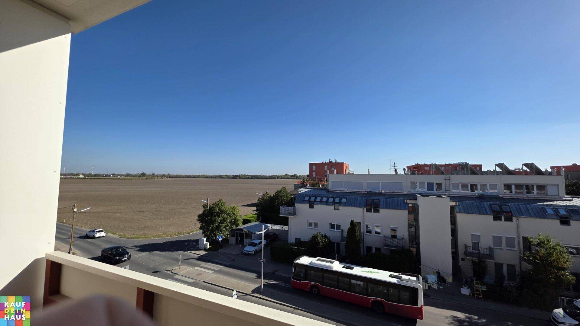 Weitblick über die Straße, angrenzende Gebäude und offene Felder.