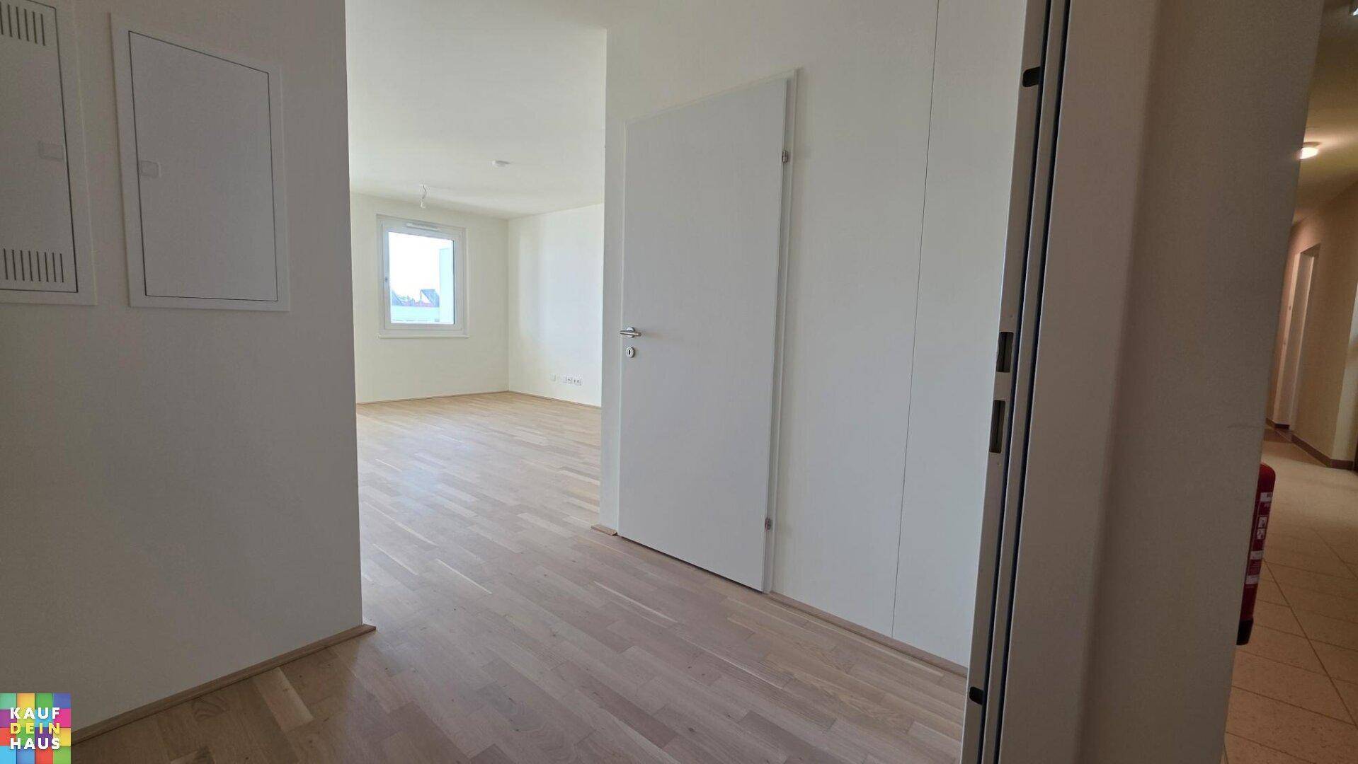 Heller Eingangsbereich mit modernem Holzparkett, der in einen weiteren Raum führt.