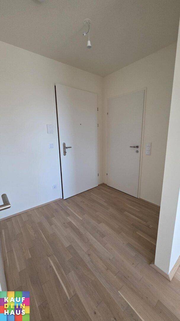 Heller Flur mit zwei Türen und modernem Holzparkett, der verschiedene Räume verbindet.