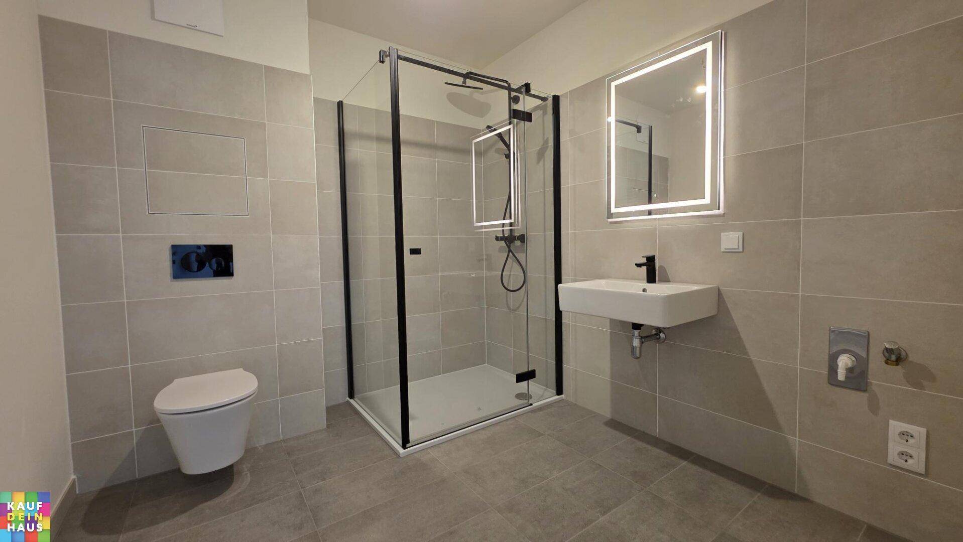 Modernes Badezimmer mit grauen Fliesen, ebenerdiger Dusche und wandhängendem WC.
