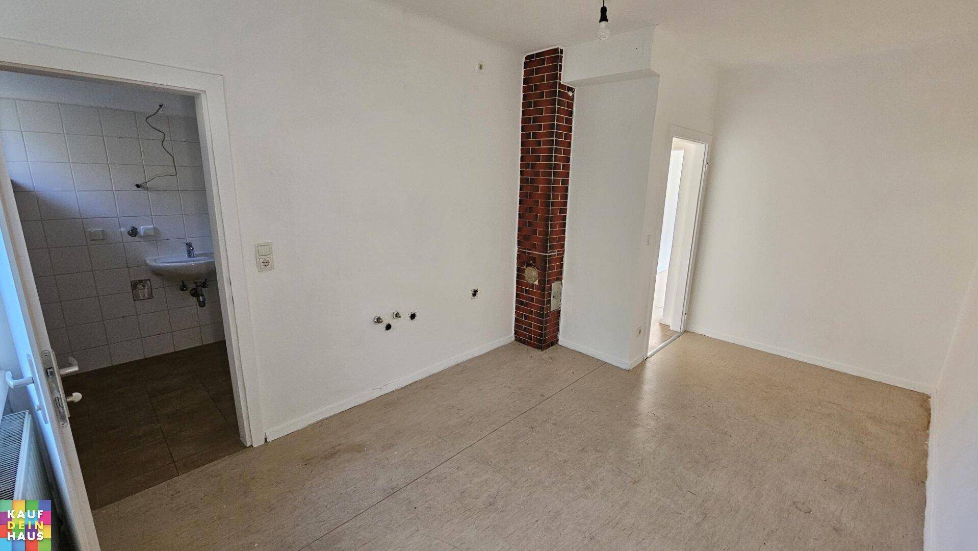 Heller Raum mit hellem Bodenbelag, Ziegelsäule und direktem Zugang zu einem gefliesten Bad.