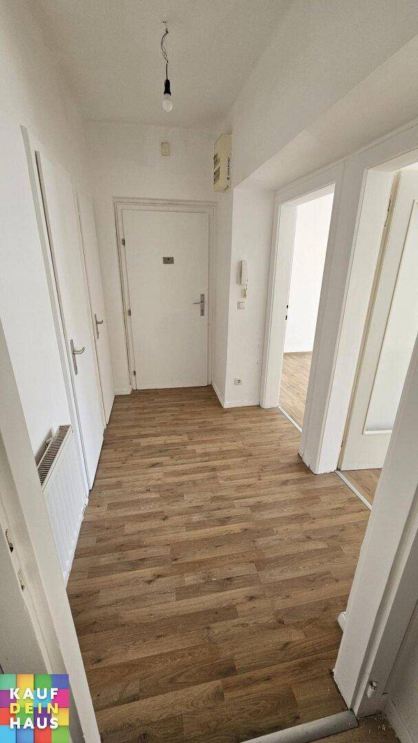 Heller Flur mit Laminatboden und mehreren Türen, inklusive Gegensprechanlage am Eingang.