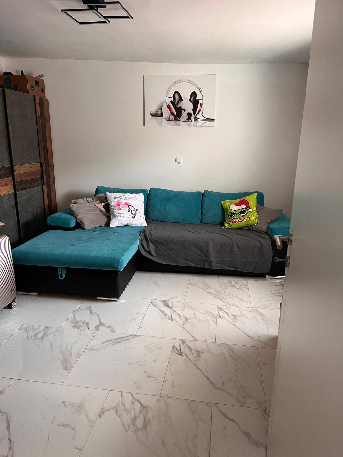 Wohnzimmer mit modernem Ecksofa und hellen Fliesen, gut beleuchtet.