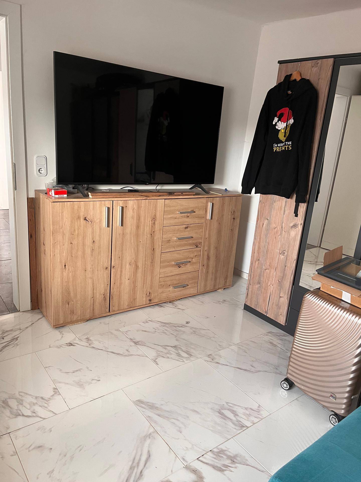 Wohnbereich mit großem Fernseher auf einem Sideboard und einem Kleiderschrank.