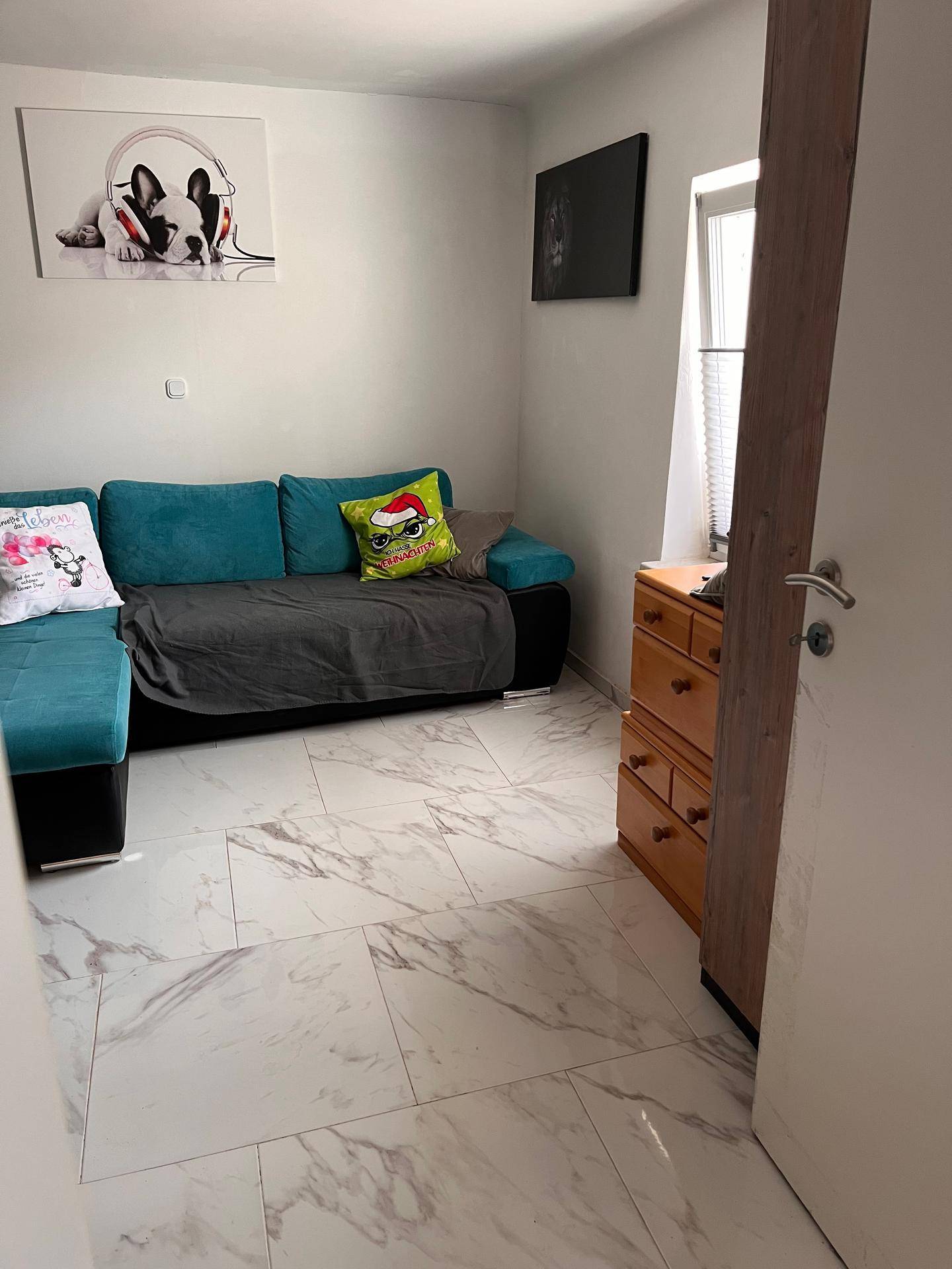 Gemütliches Wohnzimmer mit Ecksofa und hellen Marmorfliesen.