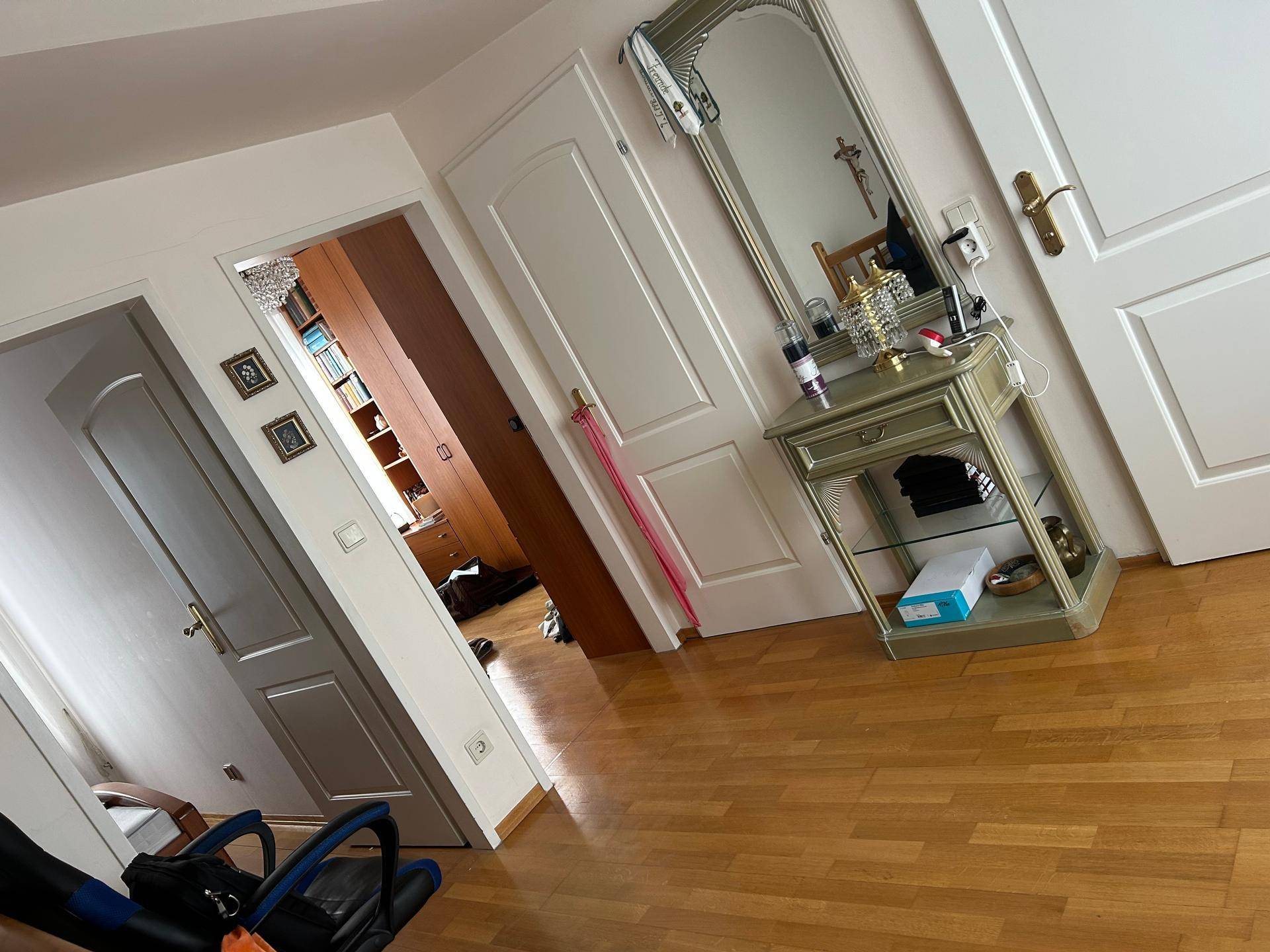 Heller Flur mit Holzboden, großem Spiegel und Zugang zu weiteren Räumen.