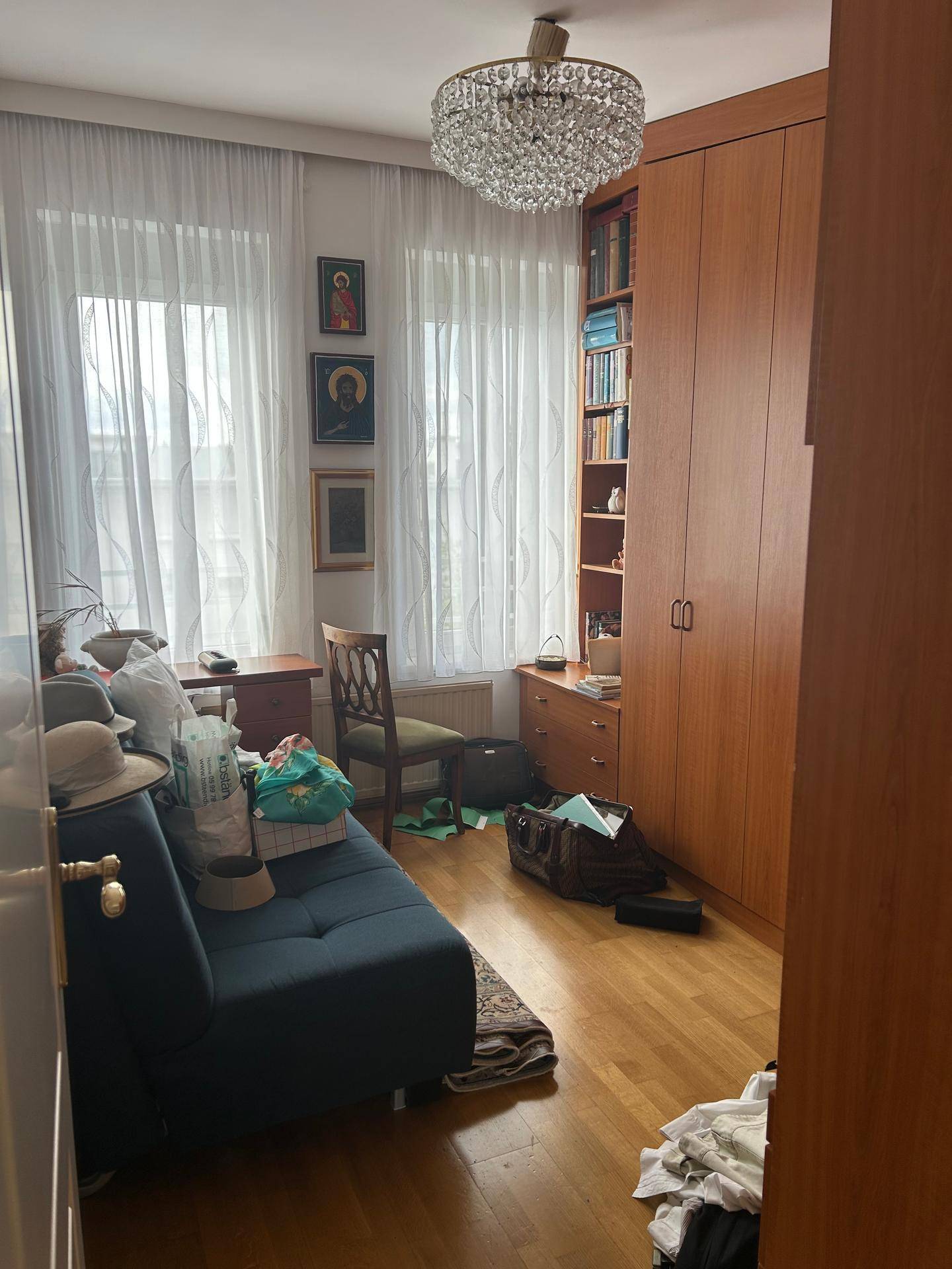 Wohnzimmer mit Sofa, Bücherregal, Schreibtisch und hellem Parkettboden.