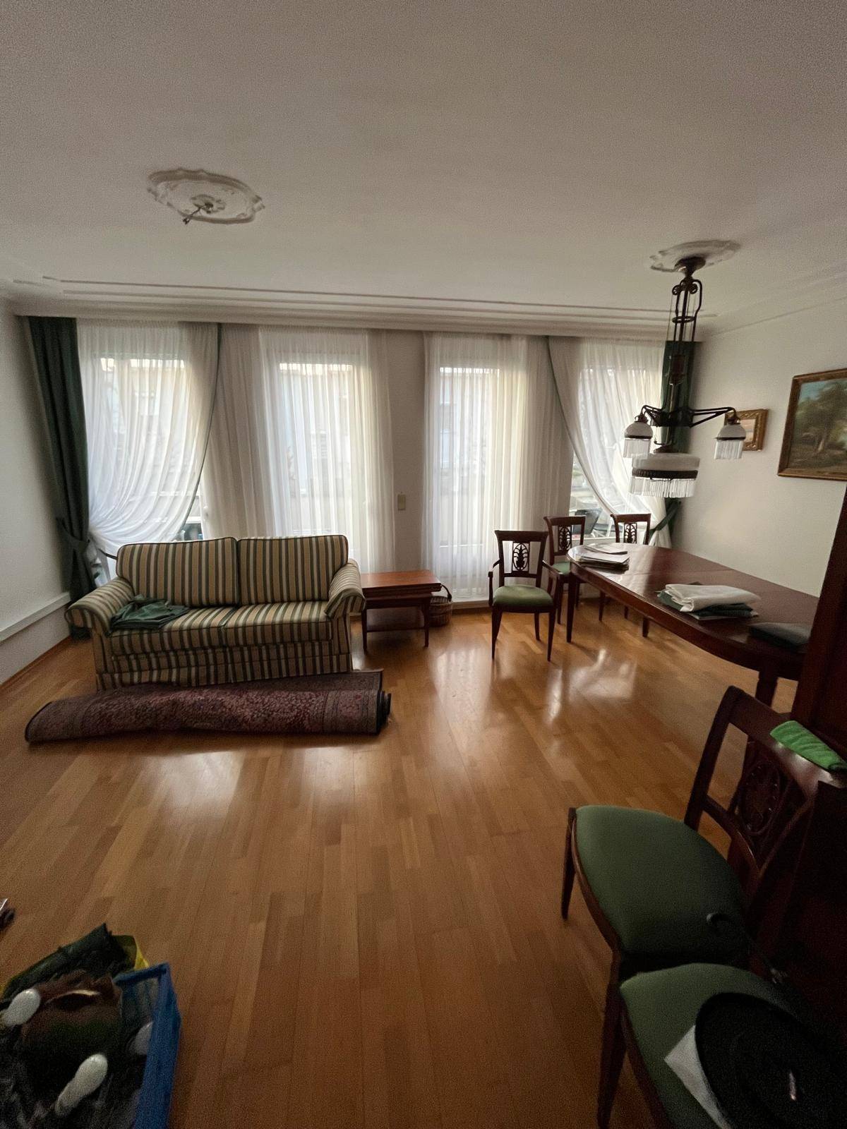 Geräumiger Wohn-Essbereich mit Parkettboden, Sofa, Esstisch und hohen Decken.