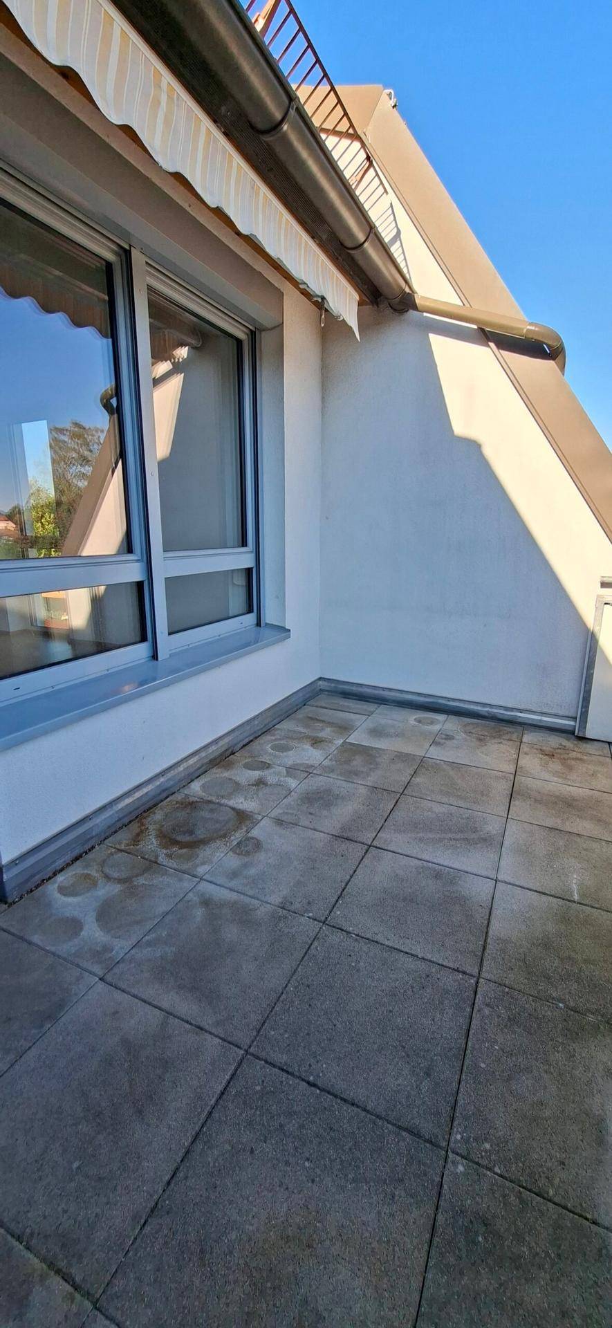 Geflieste Terrasse mit Markise und Blick auf den blauen Himmel, bereit zur Gestaltung.