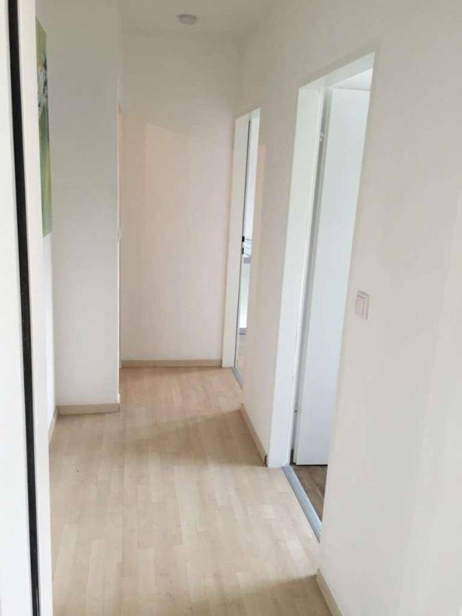 Heller Flur mit hellem Laminatboden und weißen Wänden, der zu weiteren Räumen führt.