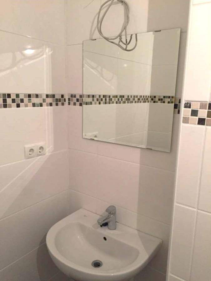 Kleines Badezimmer mit weiß gefliesten Wänden, Mosaikbordüre und Einzelwaschbecken.