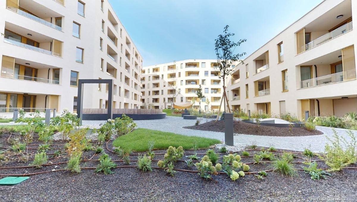 Moderner Innenhof einer Wohnanlage mit gepflegten Grünflächen und Sitzgelegenheiten.