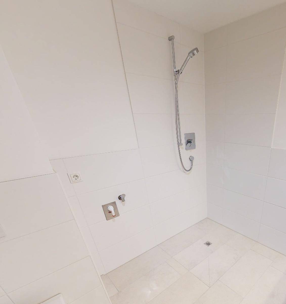 Modernes Badezimmer mit weiß gefliestem Duschbereich und Handbrause.