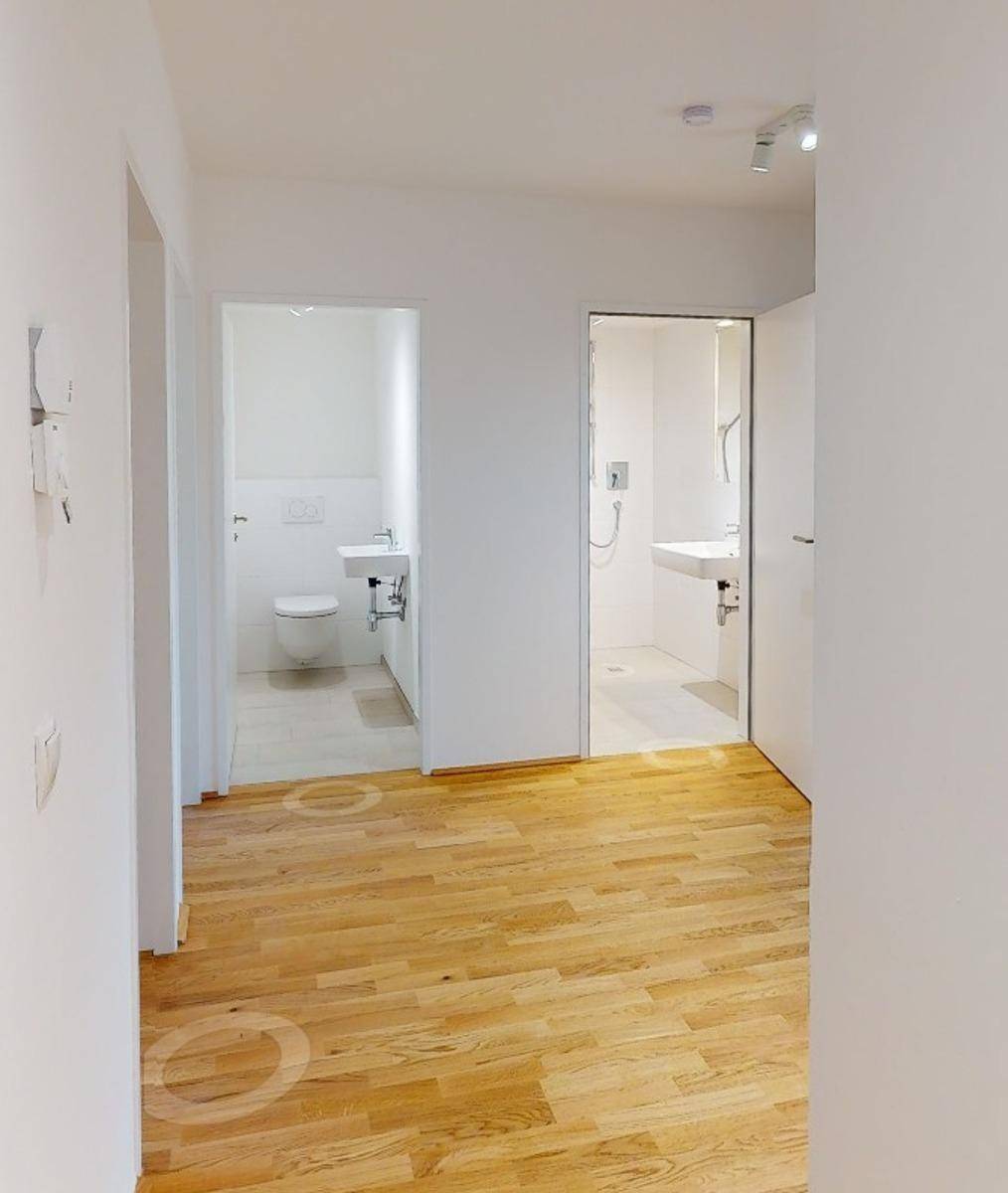 Heller Flur mit Holzboden, der zu einem separaten WC und einem modernen Badezimmer führt.