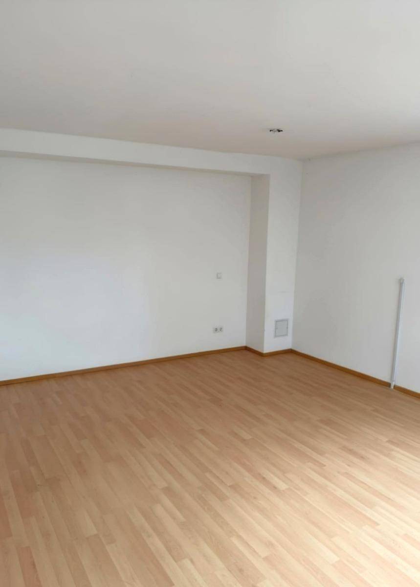 Leerer Raum mit weißen Wänden und hellem Laminatboden, bietet vielseitige Nutzungsmöglichkeiten.