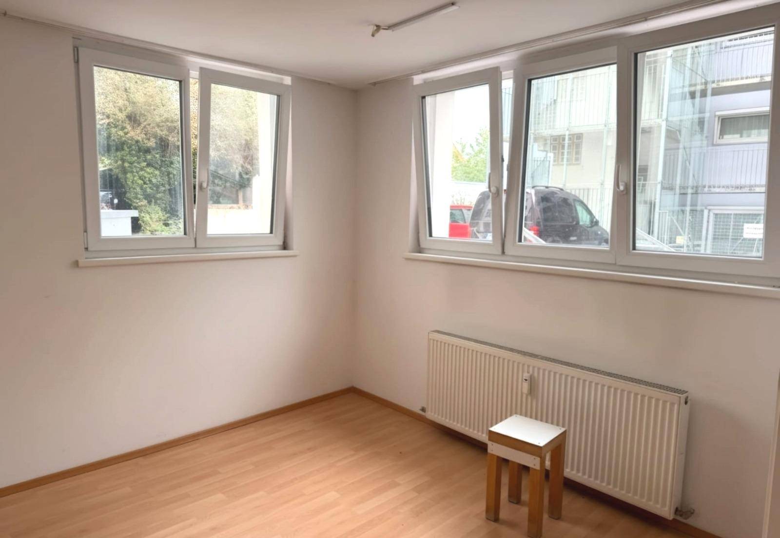 Helles Zimmer mit mehreren Fenstern, Heizkörper und Laminatboden, ideal als Schlafzimmer.
