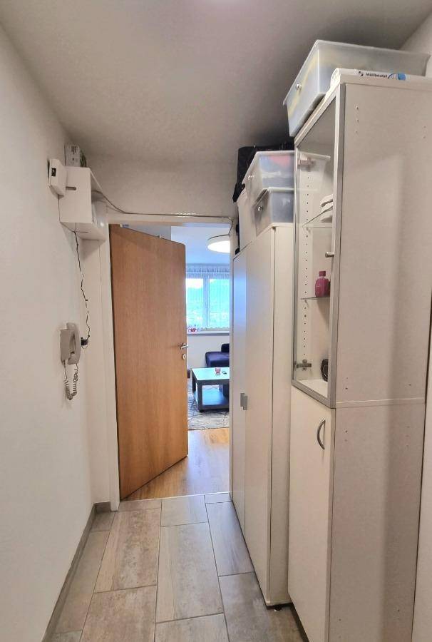 Heller Flur mit Fliesenboden und praktischen Stauschränken, der zum Wohnbereich führt.