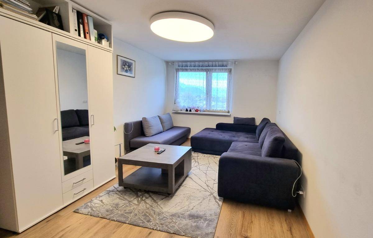 Gemütliches Wohnzimmer mit großem Ecksofa, Couchtisch und einem Kleiderschrank mit Spiegeltür.