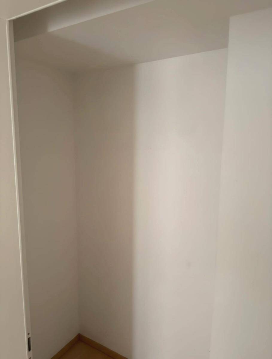Leerer Einbauschrank oder Abstellraum mit weißen Wänden und hellem Laminatboden.