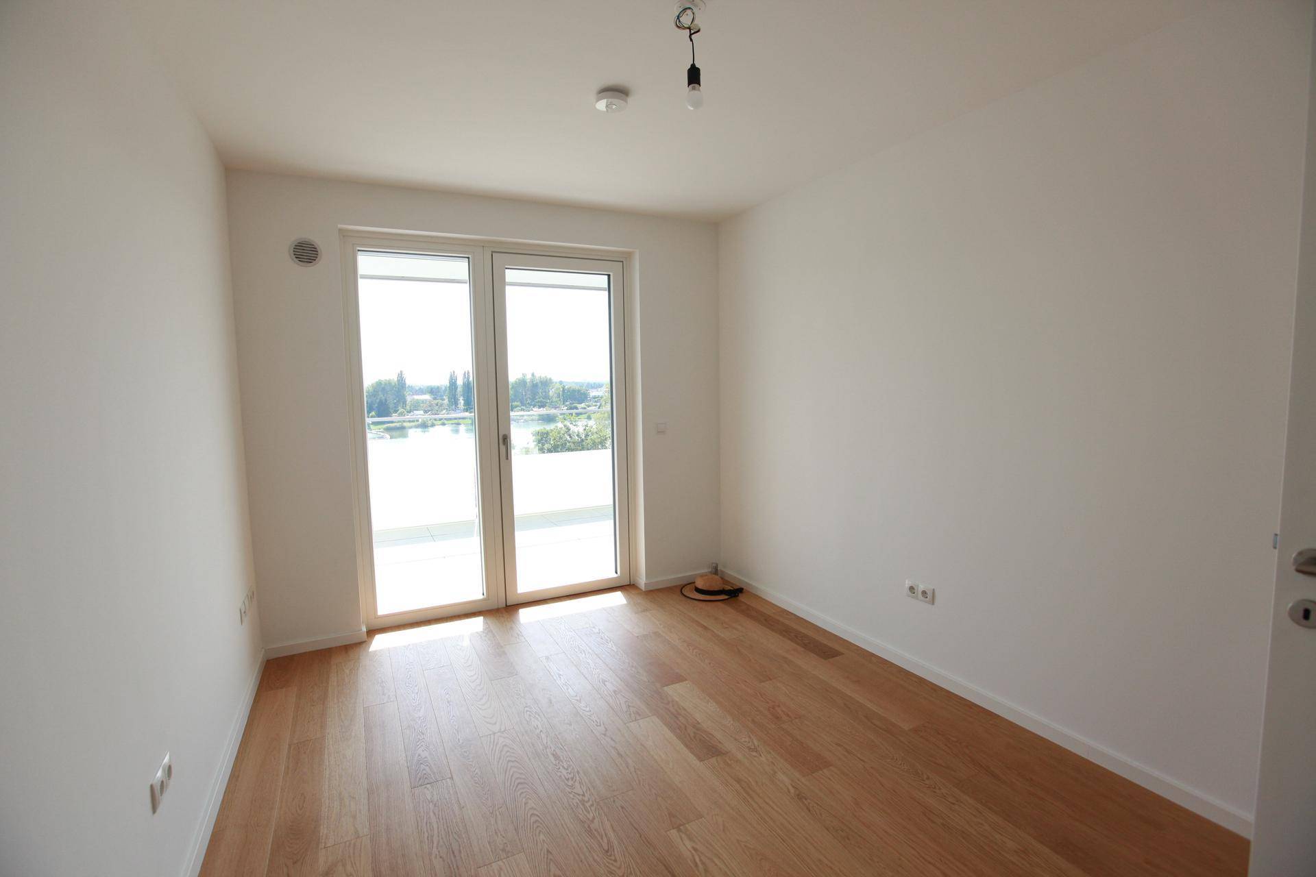Helles Schlafzimmer mit Holzboden und Balkonzugang, bietet einen schönen Blick nach draußen.