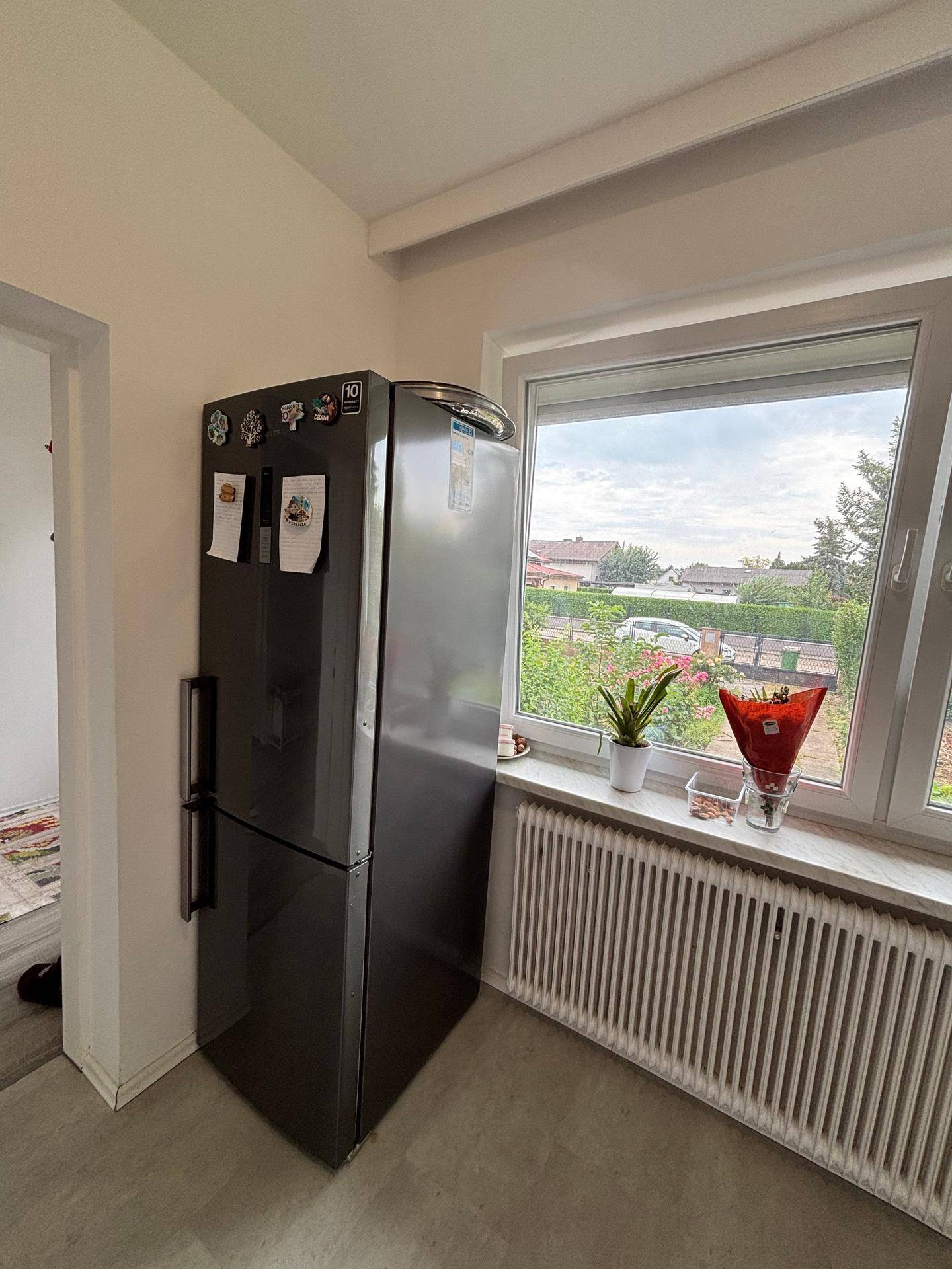 Kühlschrank in der Küche neben einem Fenster mit Blick ins Grüne.