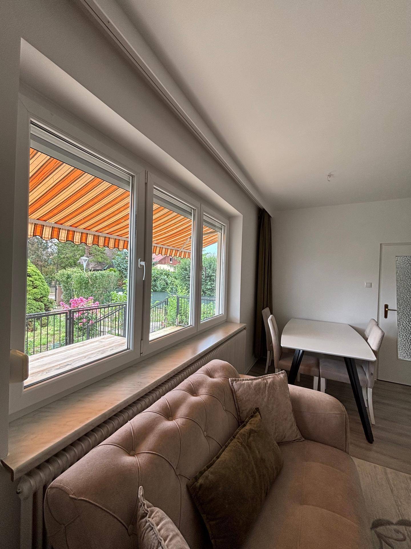 Gemütlicher Wohnbereich mit Sofa und großem Fenster, das den Blick auf die Terrasse freigibt.