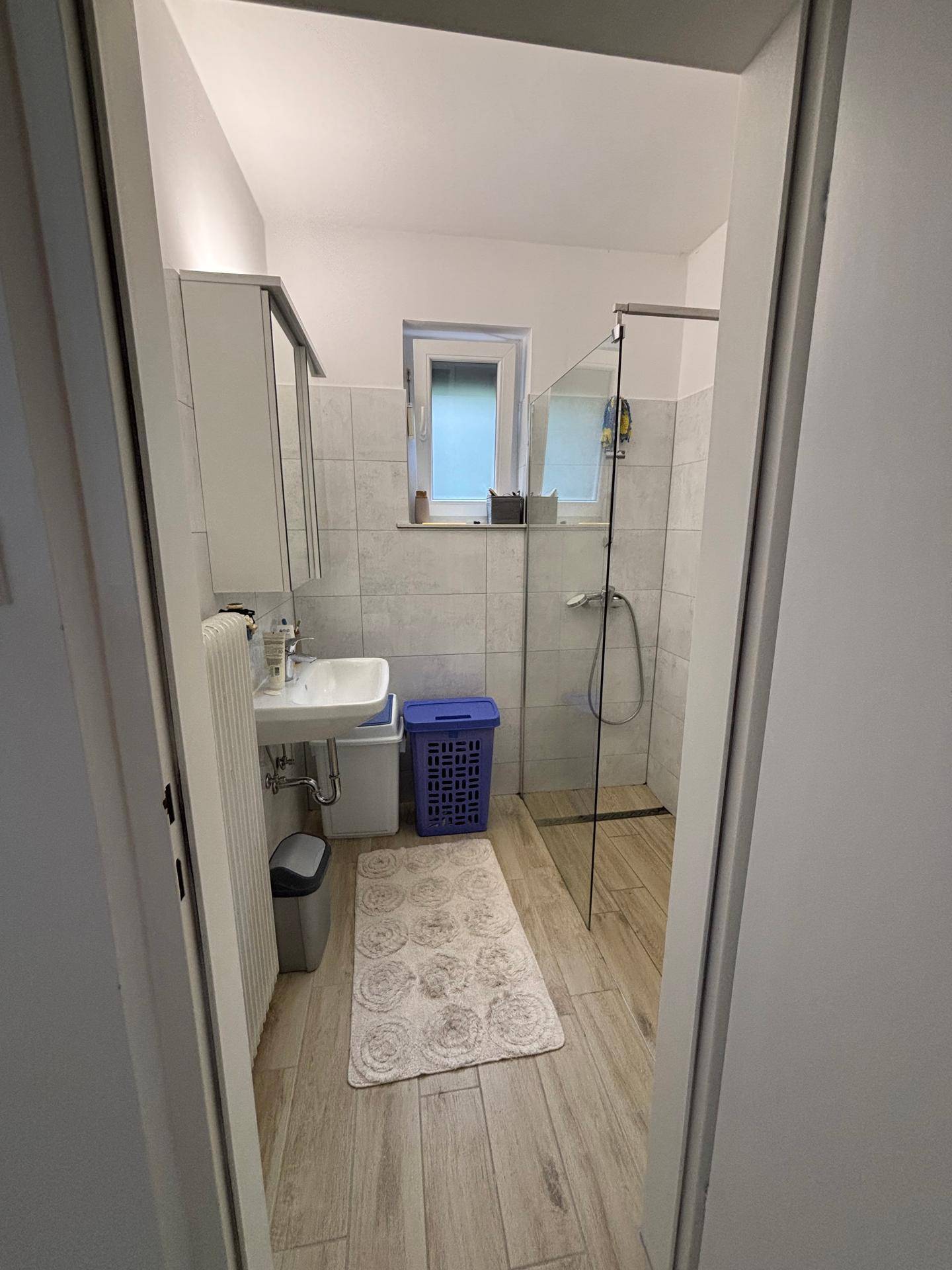 Modernes Badezimmer mit ebenerdiger Dusche, Waschbecken und Fenster.