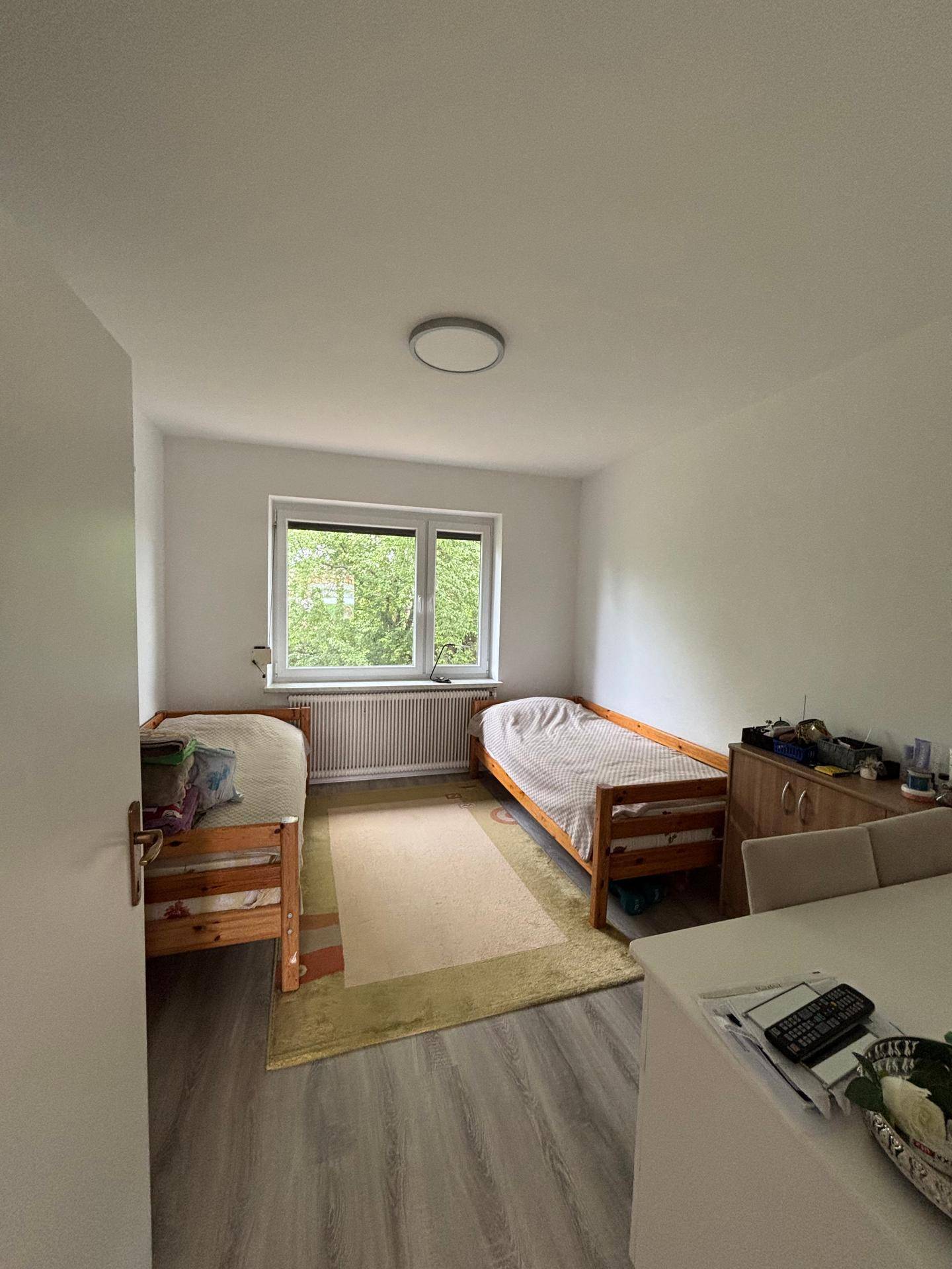 Kinder- oder Gästezimmer mit zwei Einzelbetten und einem Fenster mit Blick nach draußen.