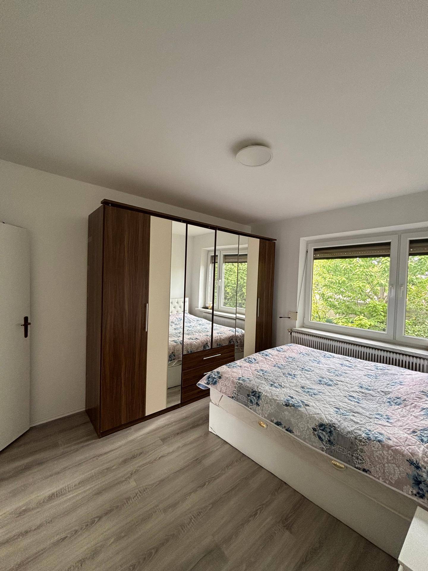 Schlafzimmer mit großem Spiegelschrank, Doppelbett und Blick ins Grüne.