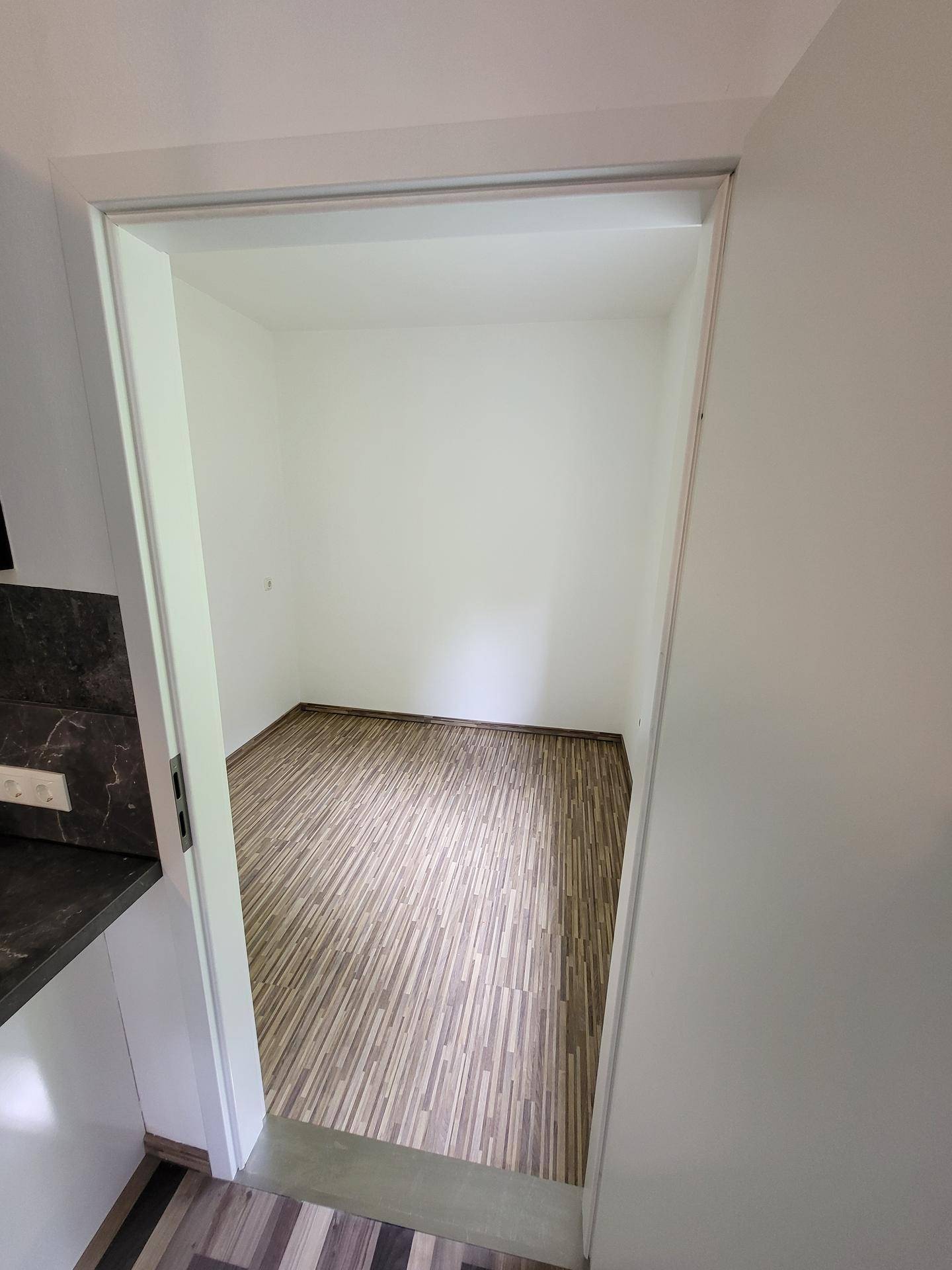 Kleiner, heller Raum mit Laminatboden, ideal als Abstellraum oder Büro.