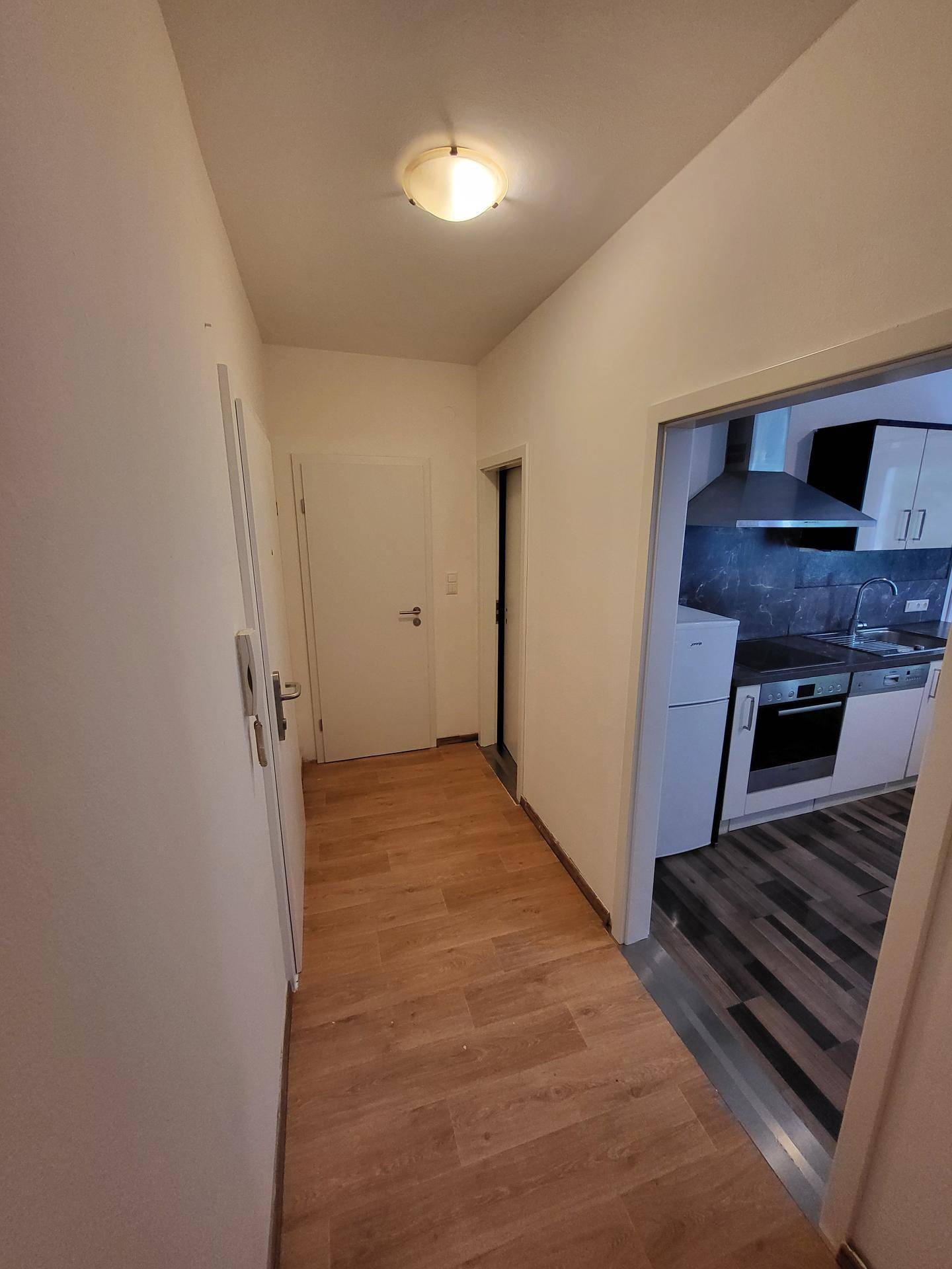 Heller Flur mit Laminatboden und Zugang zu Küche und weiteren Räumen.