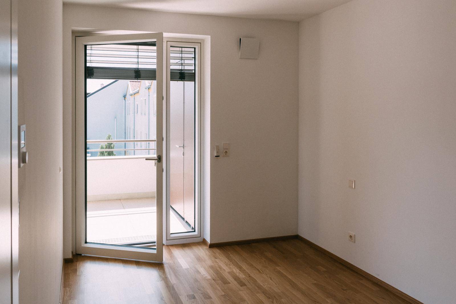 Helles Schlafzimmer mit Holzboden und direktem Zugang zu einem Balkon.