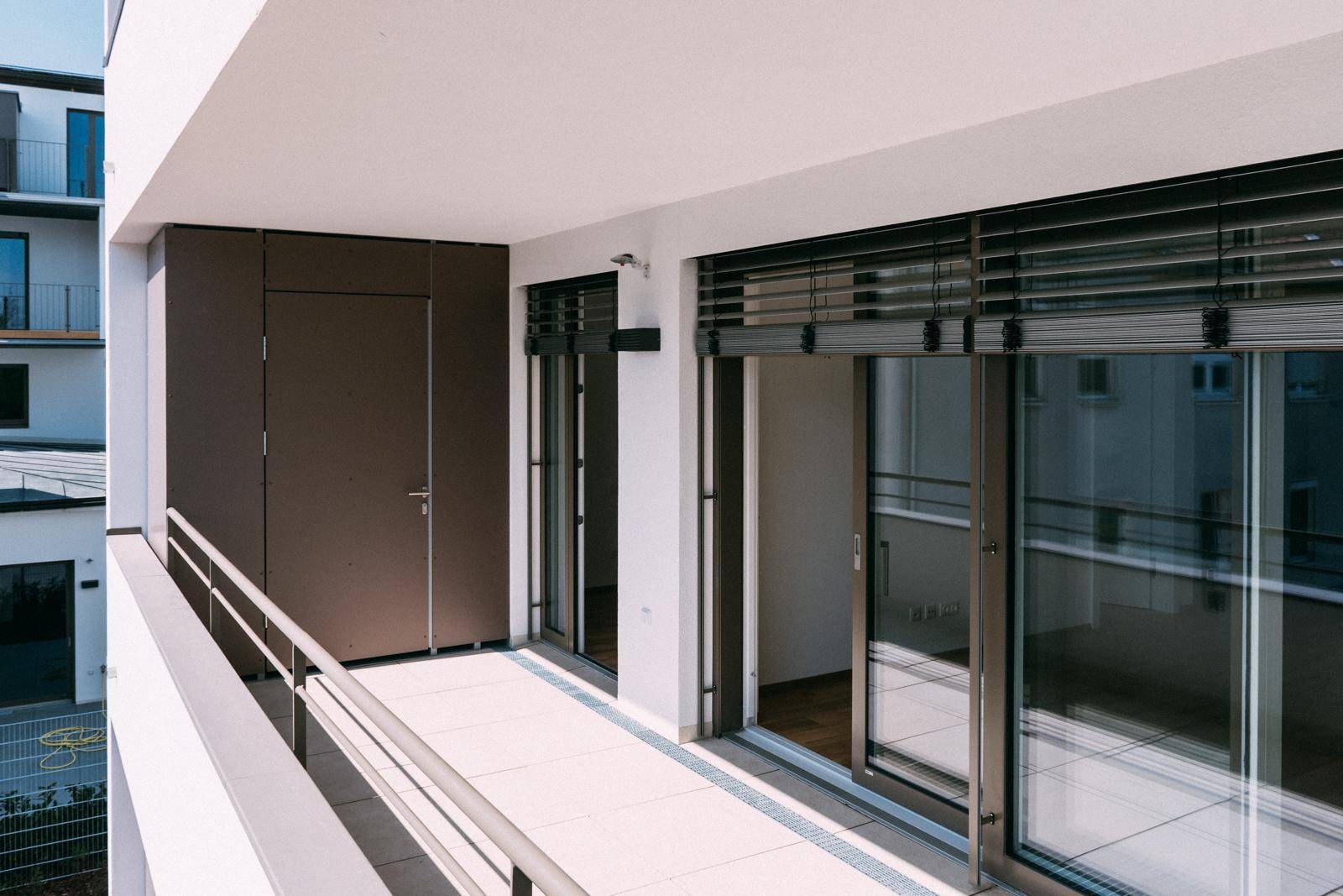 Langer Balkon mit Fliesenboden und Blick auf die umliegenden Gebäude.