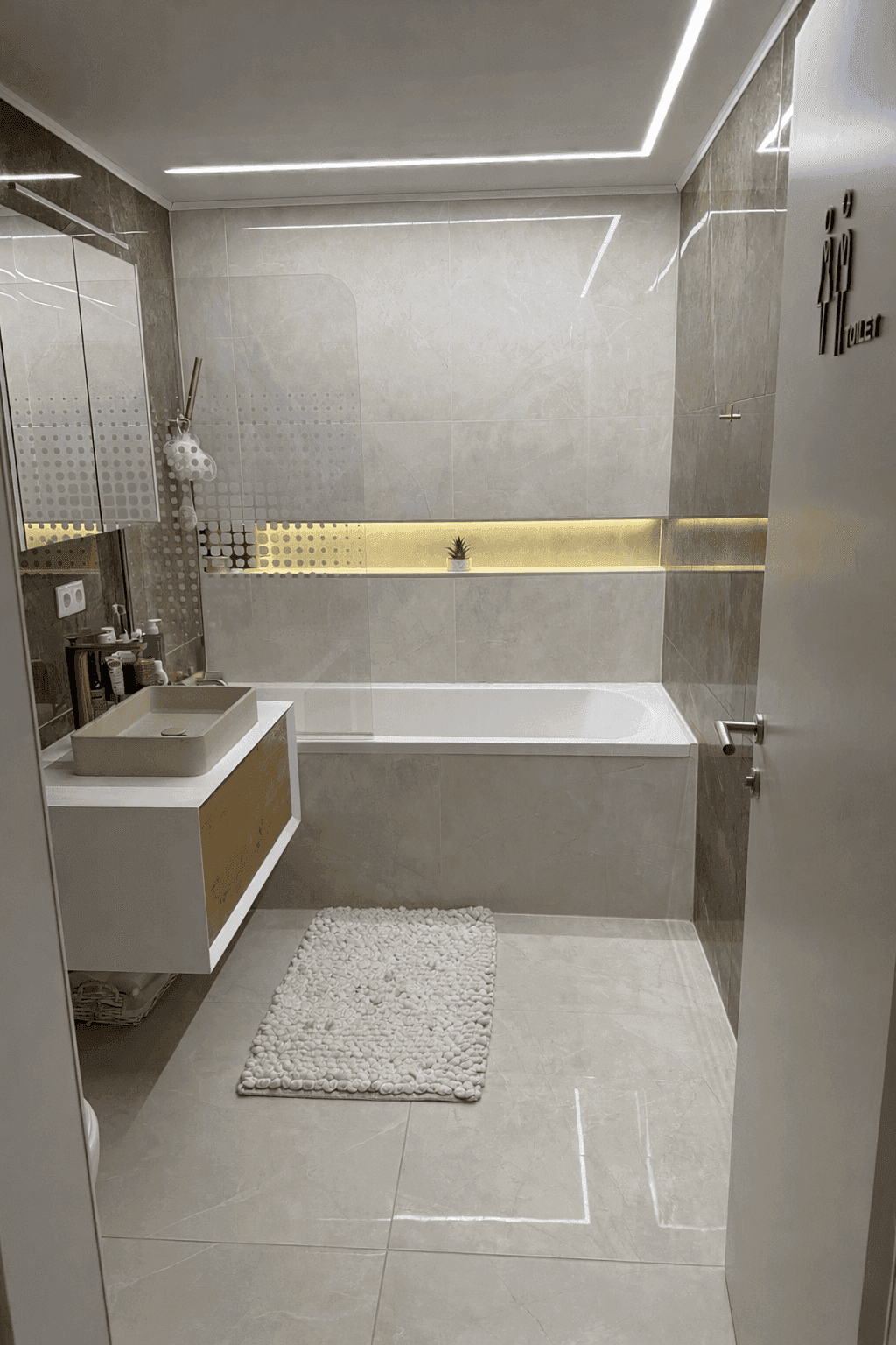 Elegantes Badezimmer mit integrierter Badewanne, modernen Fliesen und indirekter Beleuchtung.